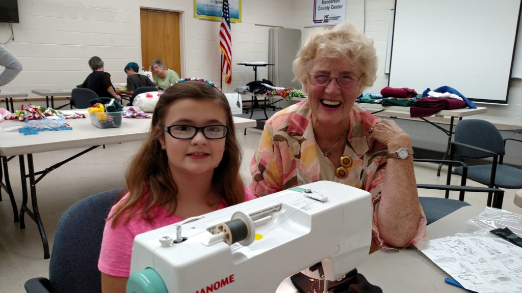 child and volunteer sewing