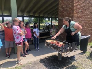 Woman grilling and talking to kids