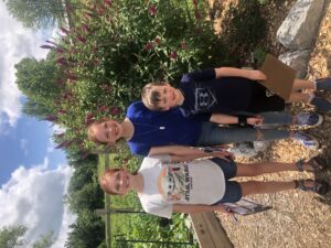 3 kids standing in front of a plant