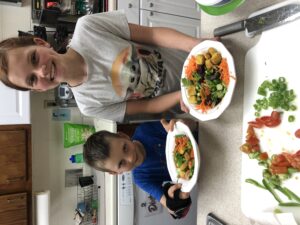 Two kids with salad bowls