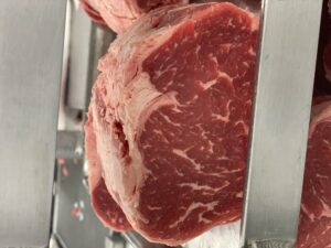 A fresh cut of beef on a stainless steel shelf.