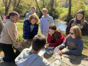 Students sit at a picnic table inspecting worksheets. 