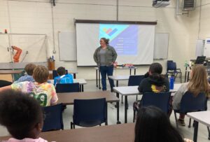 A woman gives a presentation to a group of students.