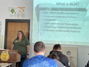 A woman teaches a group of people about Beef Quality Assurance