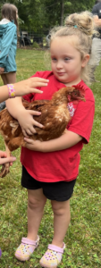 A young girl holds a chicken.