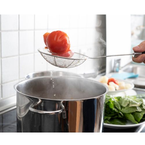 A Tomato being removed from boiling water.