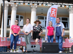 Five adults standing together on a stage. 