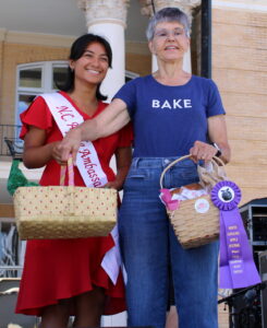 Woman on the left handing gift basket to woman on the right. 
