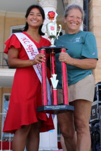 Woman on the left handing trophy to woman on the right. 