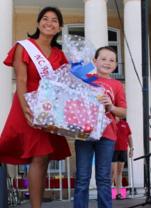 Woman on the left handing gift basket to a female child on the right. 