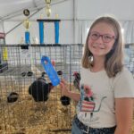 child poses with ribbon and chicken