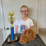 Child poses with trophy and rabbit