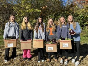 A group of girls hold boxes with harvested eggplant.
