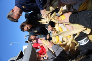 Children and adults compete in a corn shucking competition. 