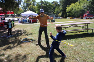 A father and son hula hoop in a park.