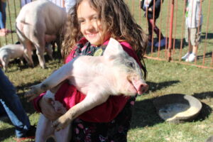 A child holds a pig in their arms.