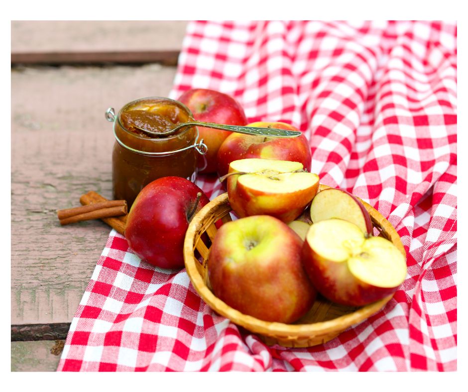 bowl of apples, jar of apple butter on a red and white gingham tablecloth