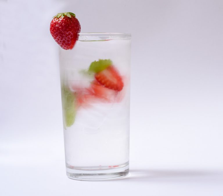 A glass of water flavored with fresh mint and strawberry.