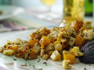 Colorful potato salad spilling out onto a plate.