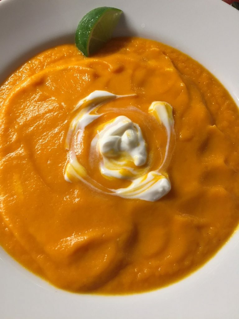 Thick Carrot Ginger soup with a cream swirl on top.