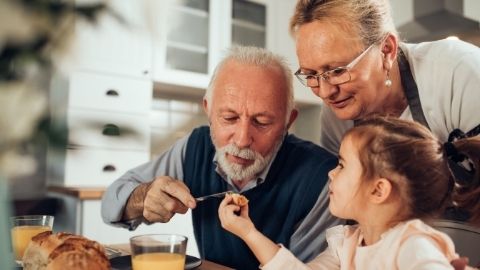 Grandparents prepare food with their granddaughter.