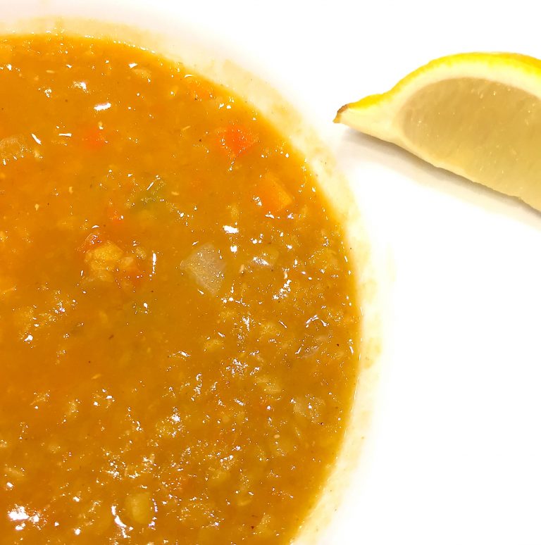 Red lentil soup with a wedge of lemon.